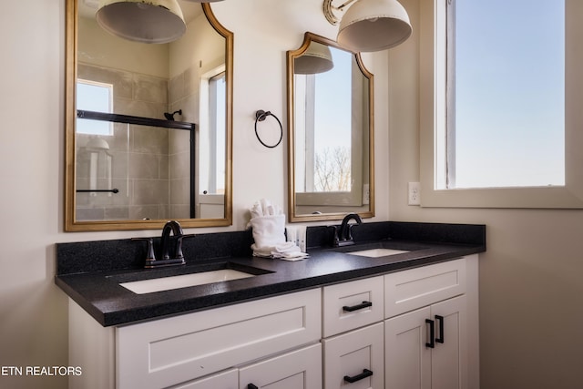 bathroom with a wealth of natural light, a shower with door, and vanity