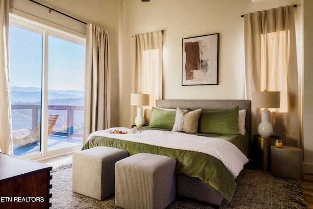 bedroom with access to exterior, hardwood / wood-style floors, and a mountain view