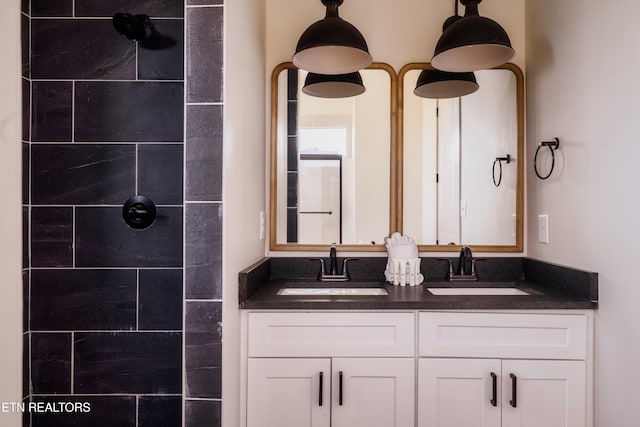 bathroom with a tile shower and vanity