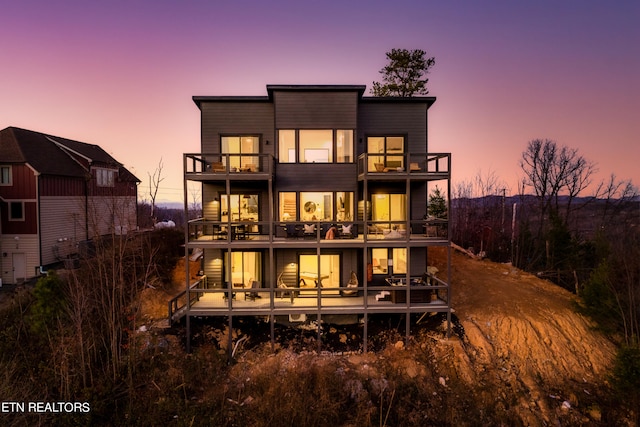 back house at dusk featuring a balcony