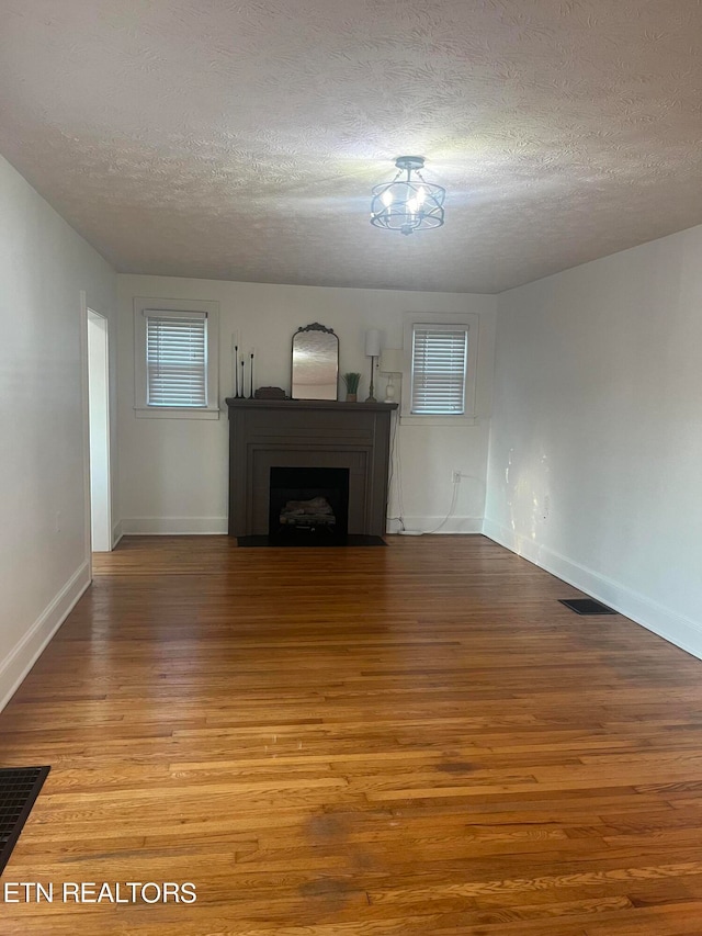 unfurnished living room featuring a textured ceiling and light hardwood / wood-style floors