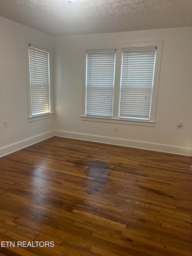 spare room with a textured ceiling and dark hardwood / wood-style flooring