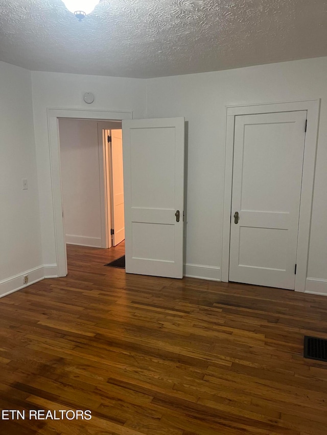 empty room featuring a textured ceiling and dark wood-type flooring