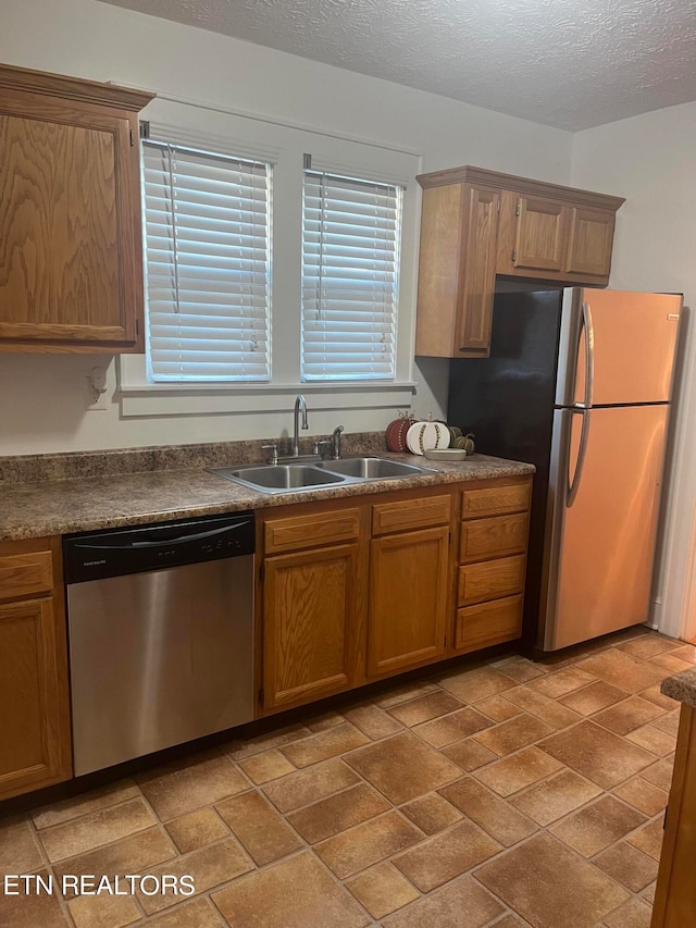 kitchen with a textured ceiling, stainless steel appliances, and sink