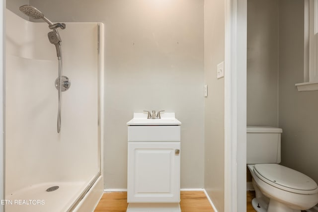 bathroom featuring wood-type flooring, a shower, vanity, and toilet