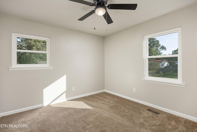 spare room with ceiling fan, plenty of natural light, and carpet flooring