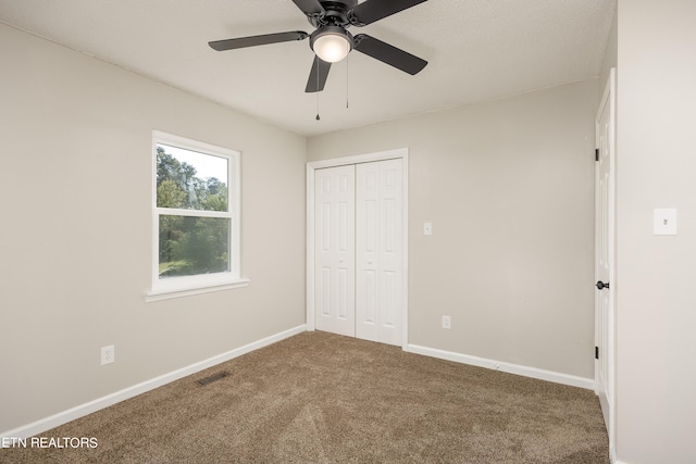 unfurnished bedroom featuring ceiling fan, a closet, and carpet