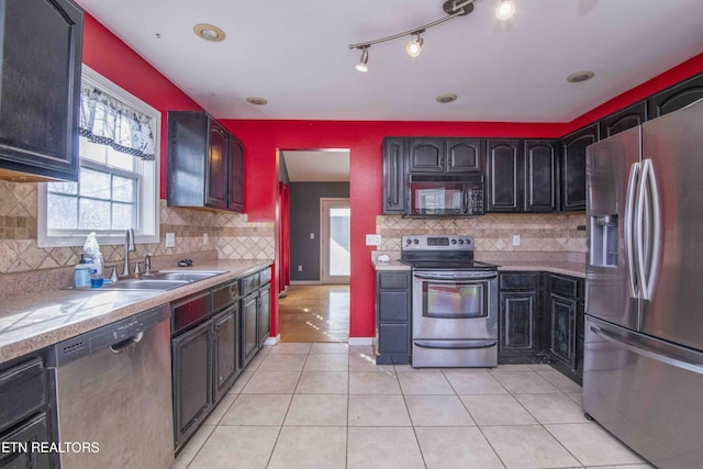 kitchen featuring light tile patterned floors, decorative backsplash, stainless steel appliances, light countertops, and a sink