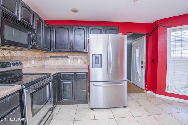 kitchen with light tile patterned floors, light countertops, backsplash, appliances with stainless steel finishes, and baseboards