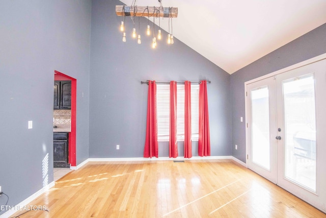 unfurnished living room featuring a healthy amount of sunlight, wood finished floors, and french doors