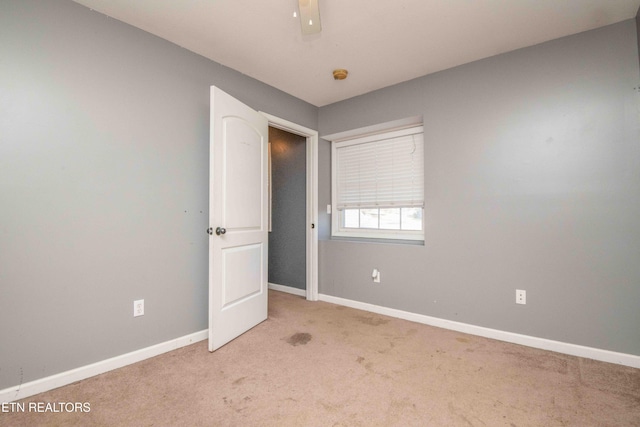 carpeted spare room featuring ceiling fan and baseboards