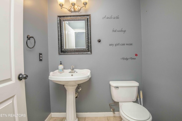 bathroom featuring toilet, tile patterned flooring, baseboards, and a notable chandelier