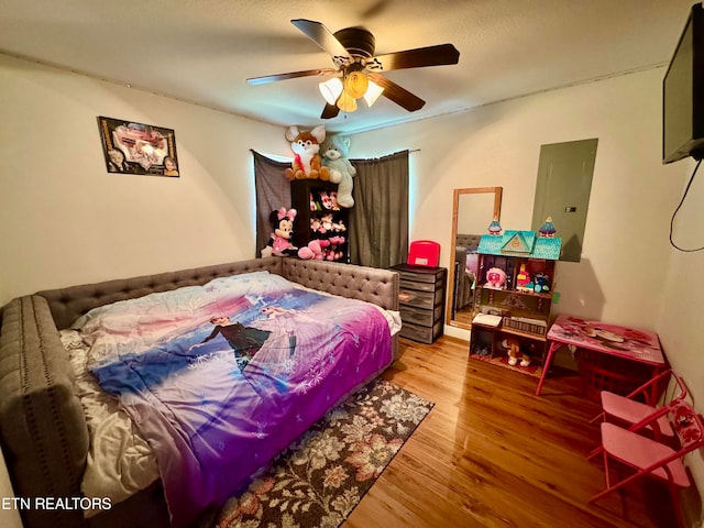 bedroom with electric panel, wood-type flooring, and ceiling fan