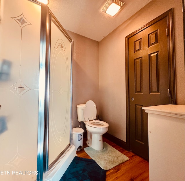 bathroom featuring a textured ceiling, an enclosed shower, hardwood / wood-style flooring, and toilet