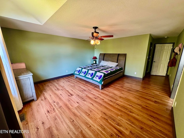 bedroom with a textured ceiling, light wood-type flooring, and ceiling fan