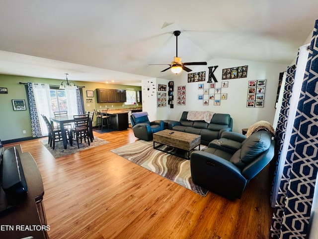 living room with light hardwood / wood-style floors, ceiling fan with notable chandelier, and lofted ceiling