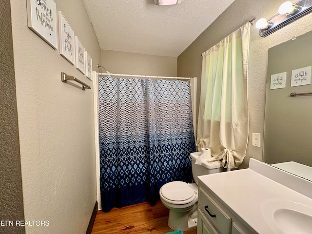 bathroom featuring a shower with shower curtain, a textured ceiling, hardwood / wood-style floors, vanity, and toilet