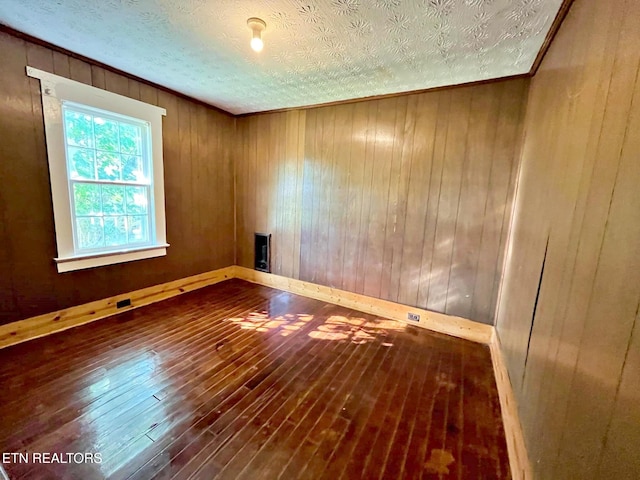 spare room featuring a textured ceiling, wooden walls, and hardwood / wood-style flooring