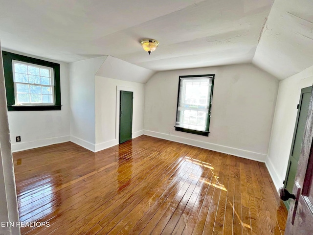 bonus room with hardwood / wood-style flooring, lofted ceiling, and a healthy amount of sunlight