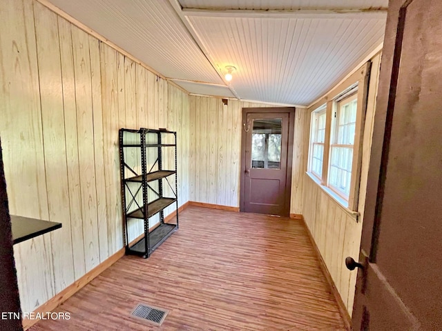 doorway to outside with wooden ceiling, light hardwood / wood-style floors, and wood walls