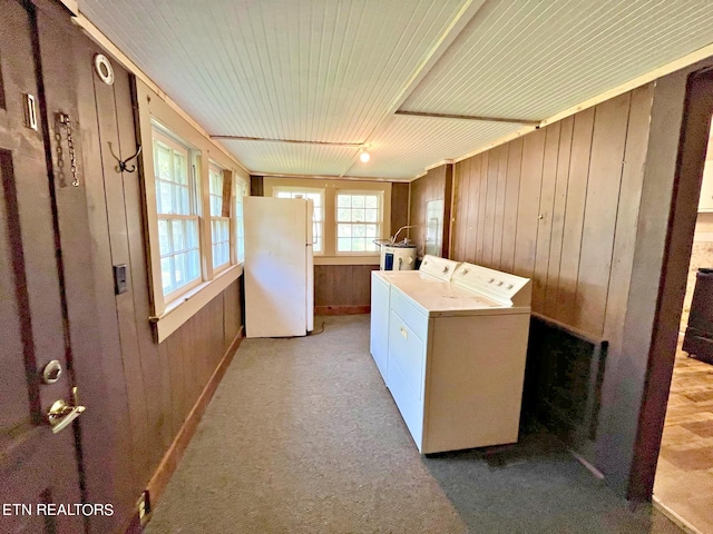 laundry room with wood walls, light carpet, and washer and dryer