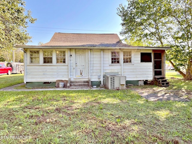 back of property featuring cooling unit and a yard