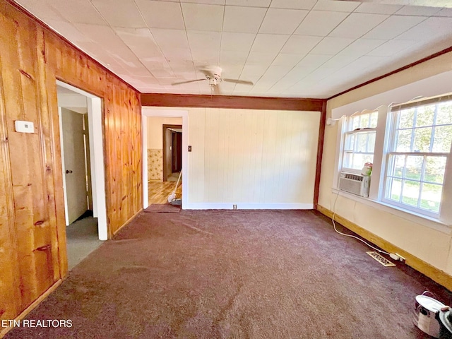 carpeted spare room with wood walls and ceiling fan