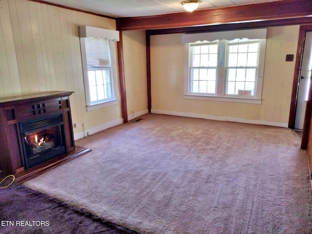 unfurnished living room with beamed ceiling, wood walls, and carpet flooring