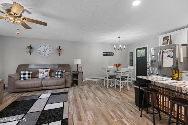 living room featuring ceiling fan with notable chandelier, a textured ceiling, light wood-type flooring, and a baseboard heating unit