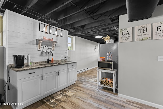 interior space with a baseboard radiator, light hardwood / wood-style floors, and wet bar