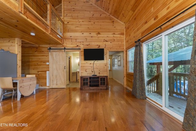 unfurnished living room featuring hardwood / wood-style floors, a barn door, high vaulted ceiling, and wood ceiling