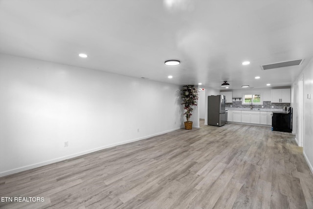 unfurnished living room featuring light wood-type flooring, ceiling fan, and sink