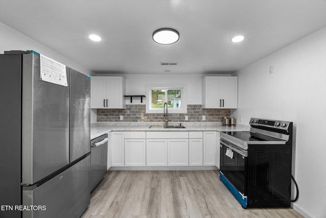 kitchen with light hardwood / wood-style flooring, white cabinetry, appliances with stainless steel finishes, and sink