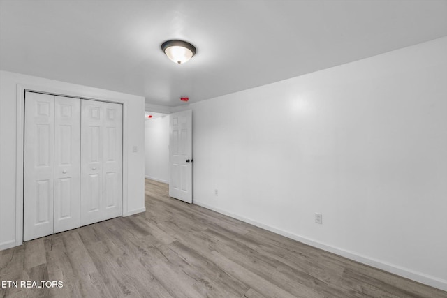 unfurnished bedroom with light hardwood / wood-style flooring and a closet