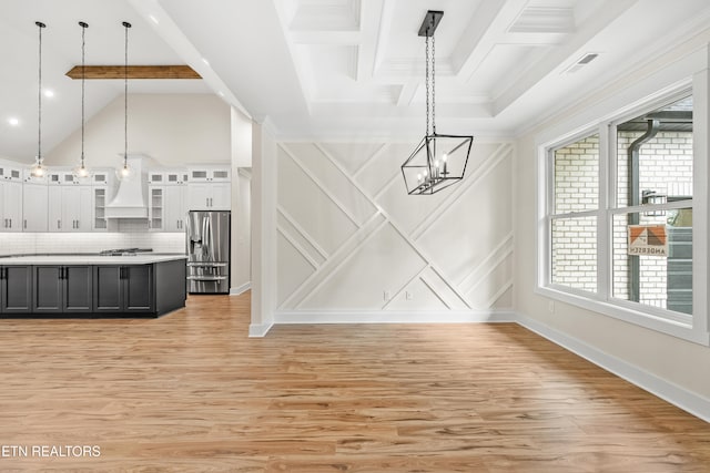 unfurnished dining area with a notable chandelier, a decorative wall, crown molding, light wood finished floors, and baseboards