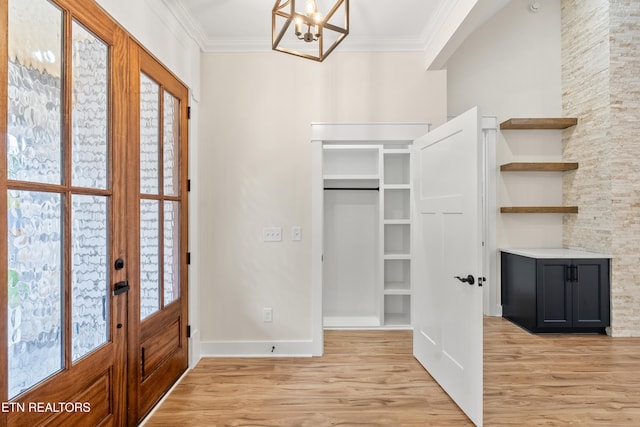 foyer featuring a chandelier, french doors, crown molding, and light wood-style floors