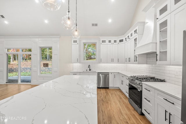 kitchen with premium range hood, visible vents, a sink, tasteful backsplash, and appliances with stainless steel finishes