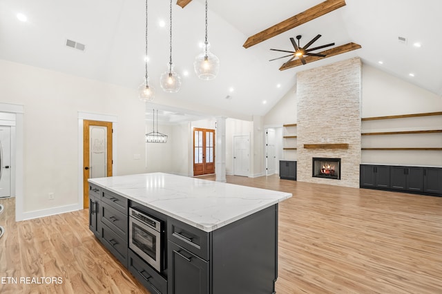 kitchen with visible vents, high vaulted ceiling, stainless steel microwave, a center island, and light wood finished floors