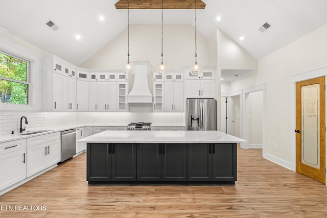 kitchen featuring premium range hood, visible vents, a sink, a kitchen island, and stainless steel appliances