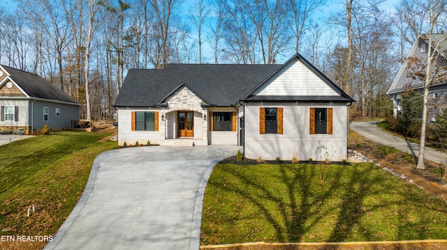 modern inspired farmhouse featuring concrete driveway, brick siding, and a front lawn