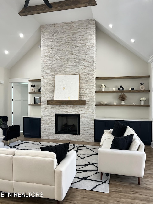 living area with beam ceiling, a fireplace, high vaulted ceiling, and wood finished floors