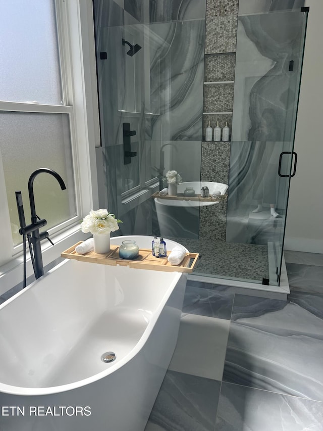 bathroom featuring a shower stall, a freestanding tub, marble finish floor, and a sink