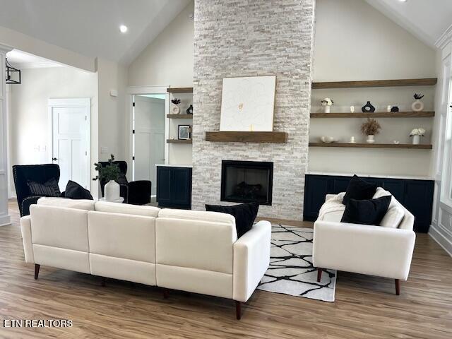 living room with wood finished floors, recessed lighting, a fireplace, and high vaulted ceiling