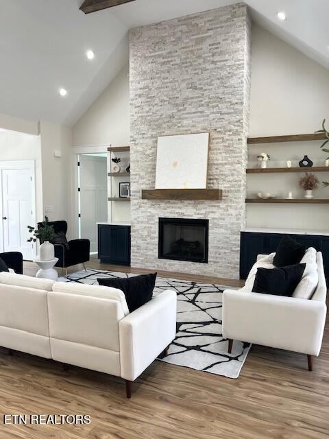 living room featuring beamed ceiling, a stone fireplace, recessed lighting, wood finished floors, and high vaulted ceiling