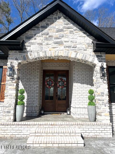 doorway to property with french doors, brick siding, and stone siding