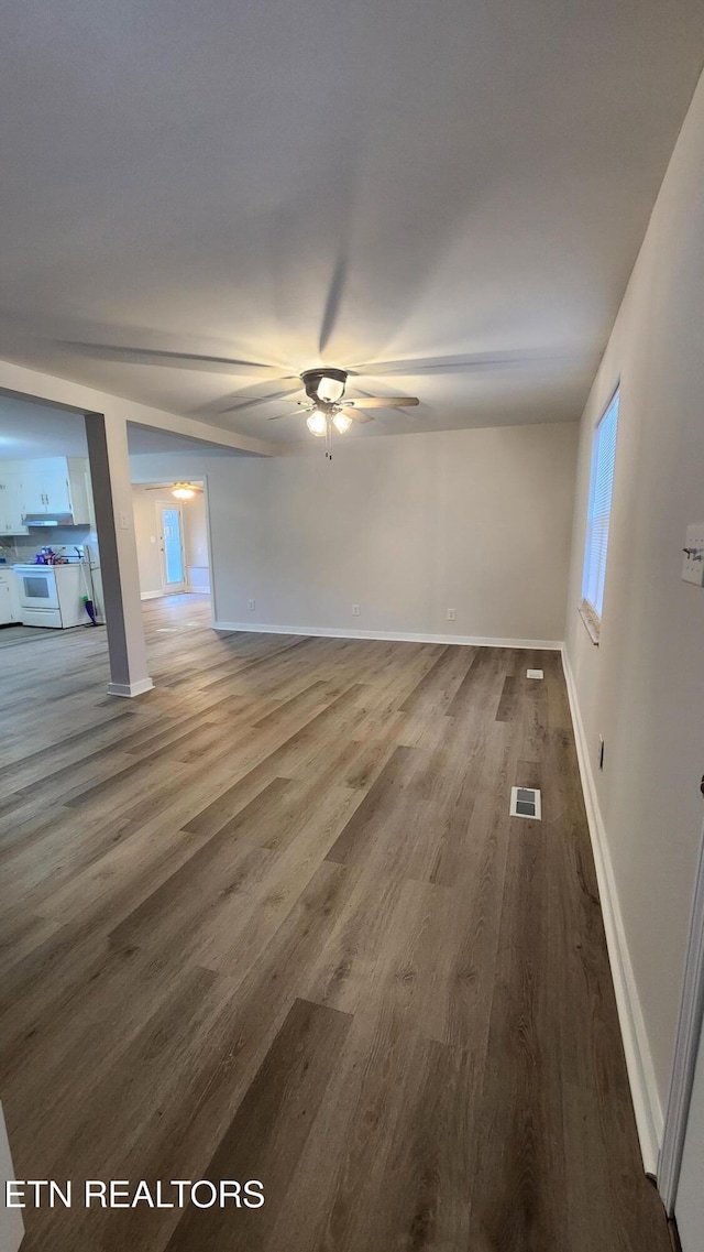 unfurnished living room with baseboards, ceiling fan, visible vents, and wood finished floors