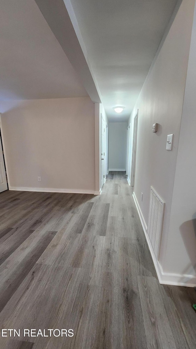 corridor featuring visible vents, baseboards, and wood finished floors