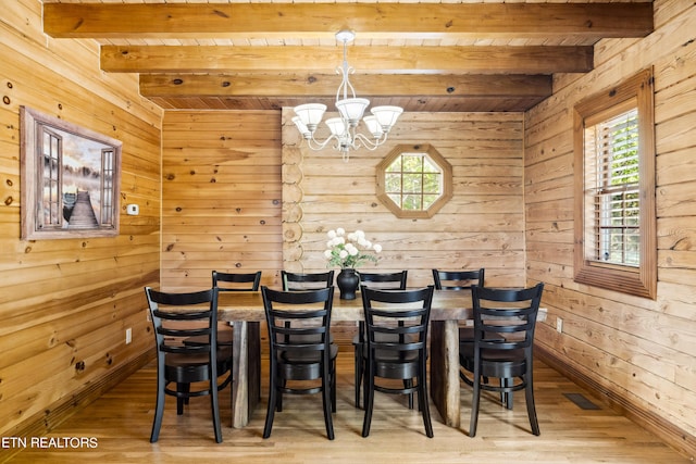 dining area with beam ceiling, wooden walls, a chandelier, and hardwood / wood-style flooring