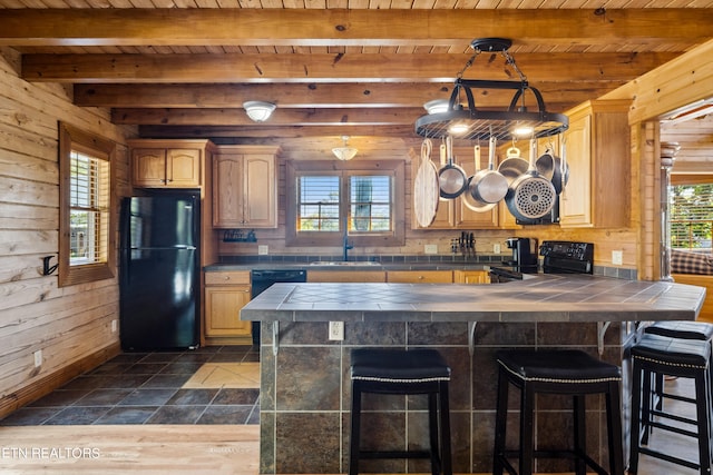 kitchen featuring wood ceiling, a breakfast bar area, black appliances, wooden walls, and dark hardwood / wood-style floors