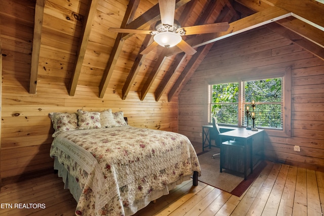 bedroom with light wood-type flooring, vaulted ceiling with beams, wood walls, and ceiling fan